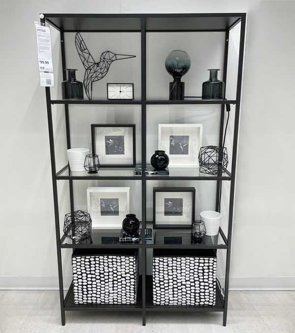 Black shelf with black and white decor, frames, pots, clock, lamp